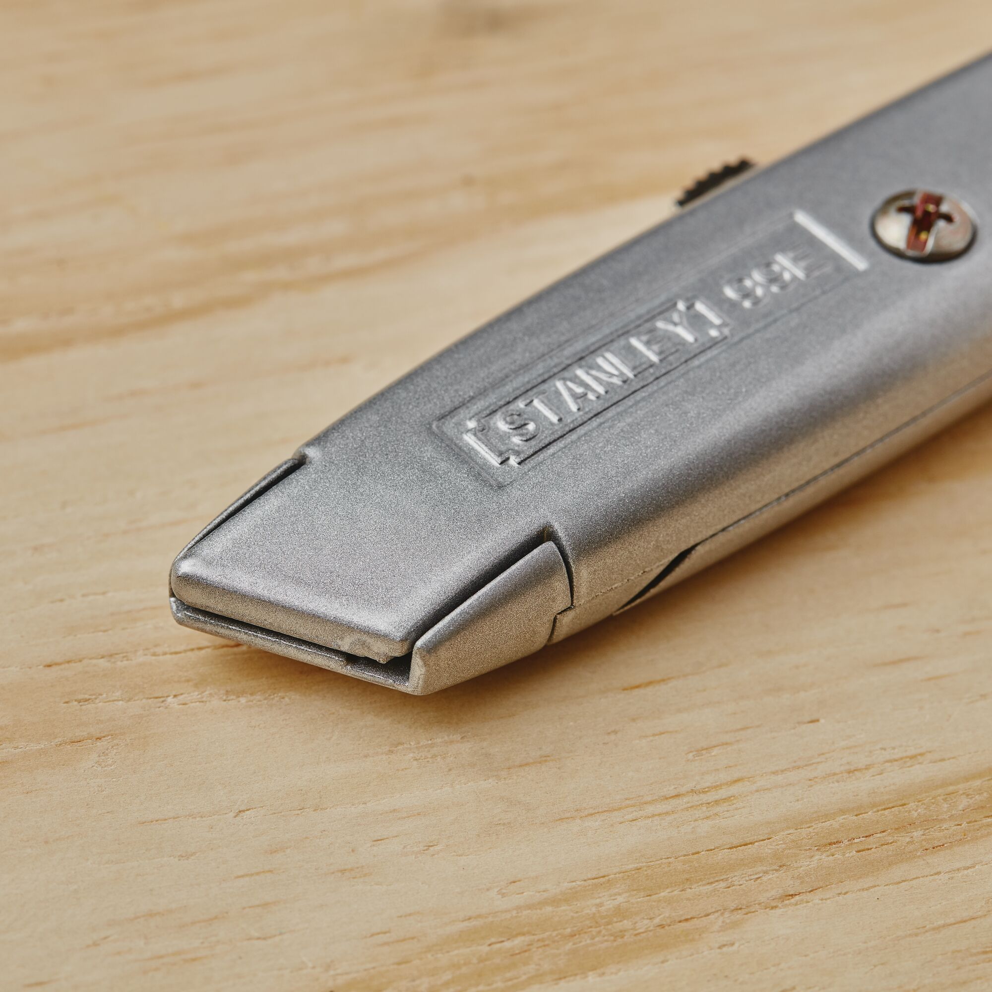 Stanley 10-099 utility knife, silver metal body, photographed close-up on a wooden surface.
