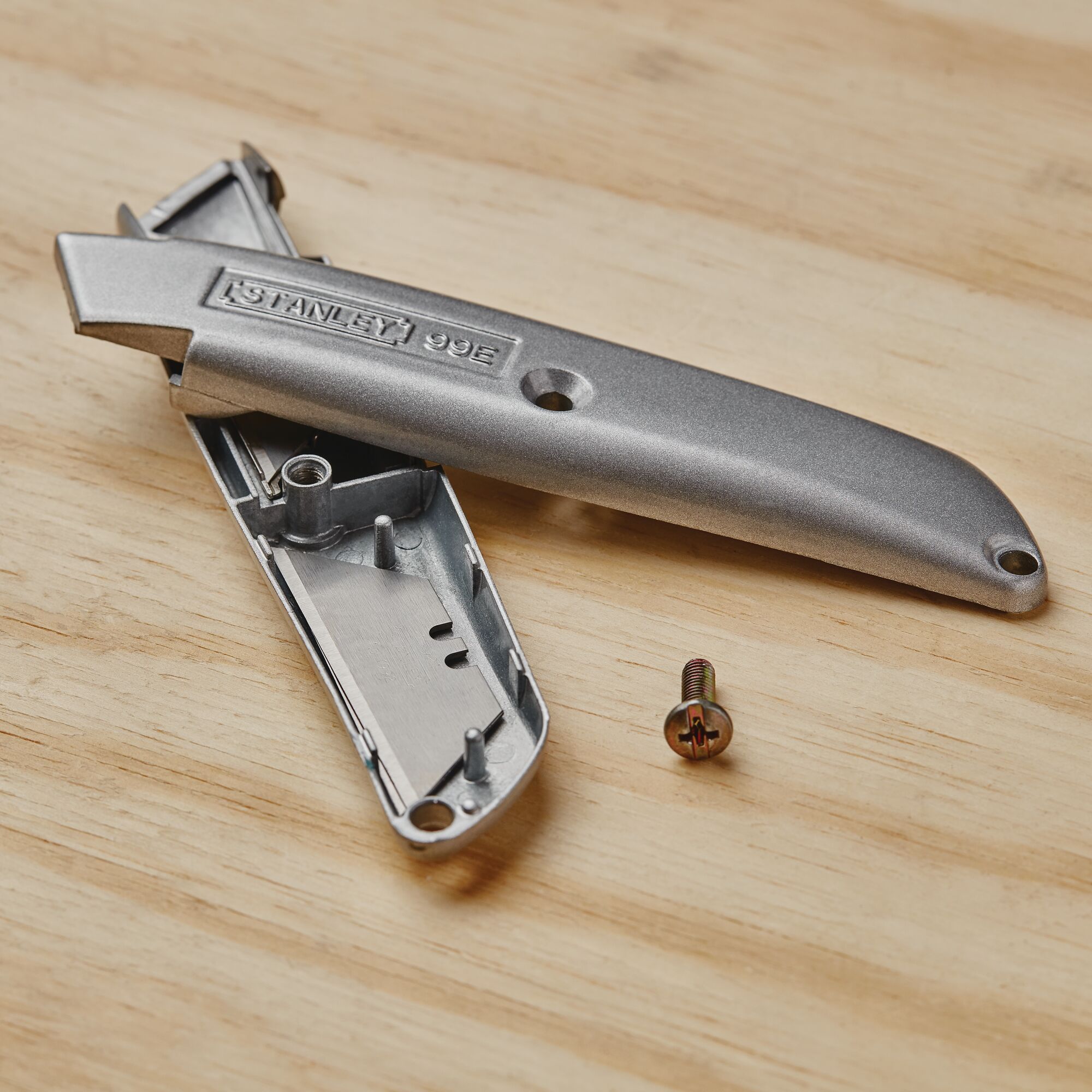 STANLEY 10-099 utility knife casing and screw on wooden surface, photography of tool parts.