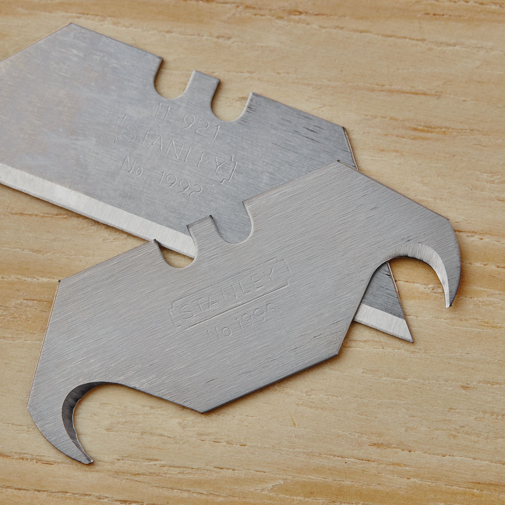 STANLEY 10-099 utility hook blades, close-up on flat wooden surface.