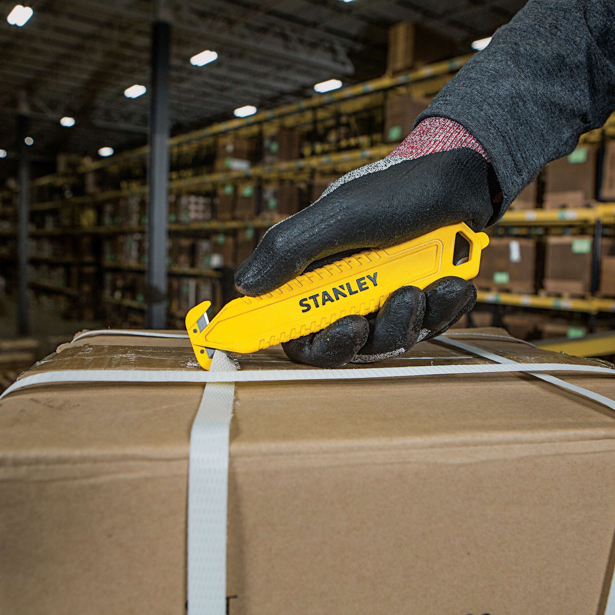 Double Sided Pull Cutter being used for cutting plastic packing rope on cardboard box.