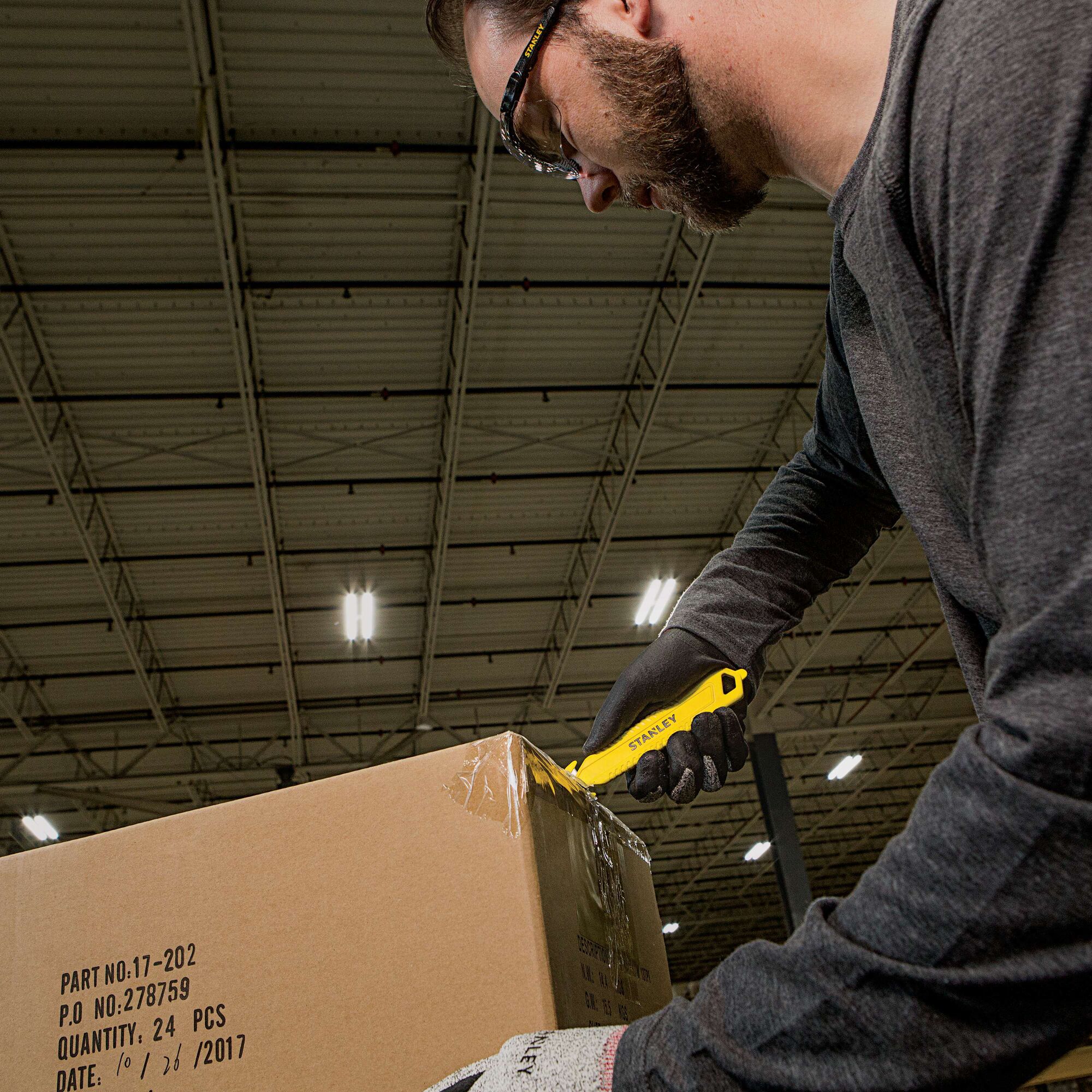 Double Sided Pull Cutter being used for cutting cello tape on cardboard box.