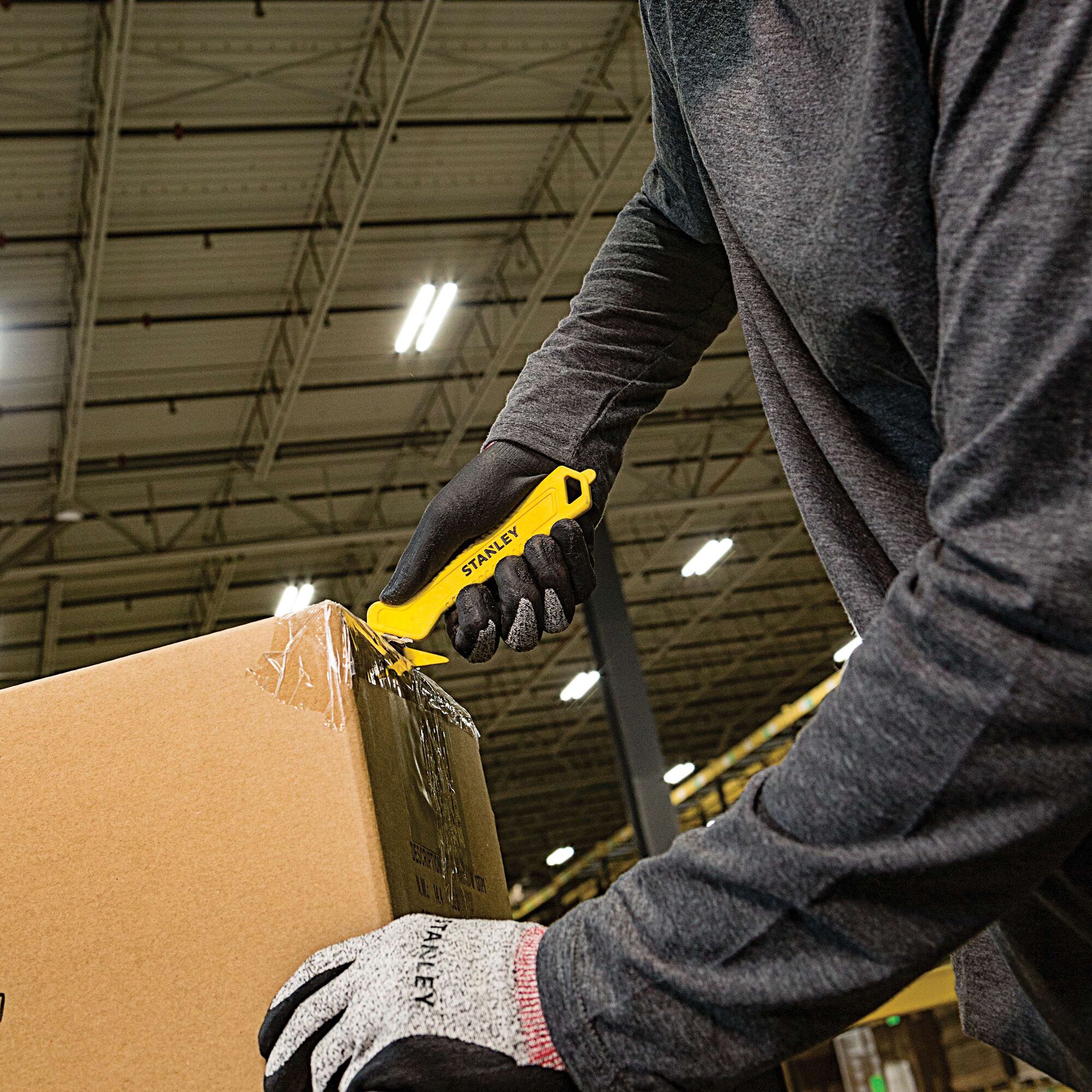 STANLEY STHT10355 yellow safety knife cutting box tape in warehouse, close-up photography.